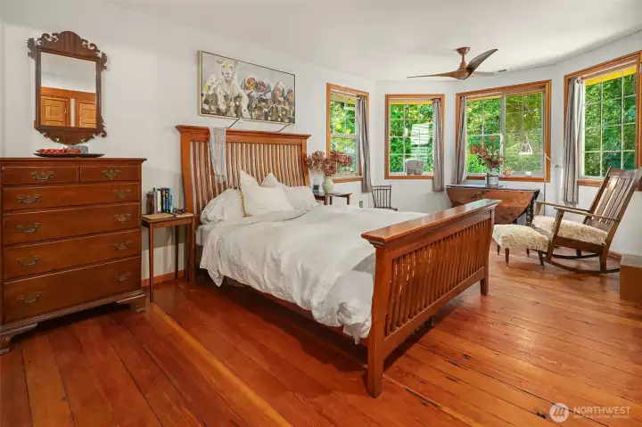 Primary bedroom with lovely sitting area surrounded by windows. What a sweet retreat from a busy life!