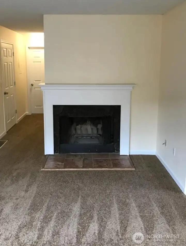 Fireplace with mantel, entry to the left, bath, laundry, and bedrooms down the hall. Kitchen and living room to the right.