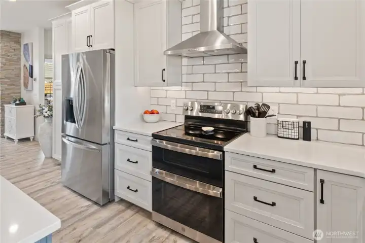 Subway tile, stainless steel appliances, a farmhouse sink, and quartz countertops come together to create a beautiful and well-appointed kitchen space.