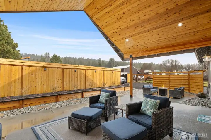 A secondary sitting area is thoughtfully tucked within the fenced patio, offering a private and comfortable spot to converse around a firepit, or just relax and unwind.