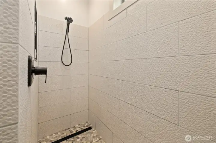 The custom-tiled shower delivers a luxurious, spa-like experience with high-end finishes and thoughtful design.