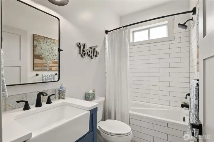 The shared bath features striking white subway tile paired with custom ceramic tile flooring, creating a clean and timeless finish.
