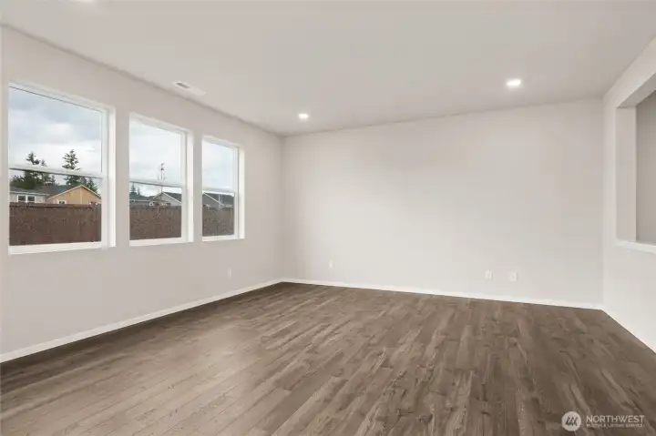 Bright living room featuring three large windows and natural light. Photos are representative only and may display different color packages and/or upgrades.