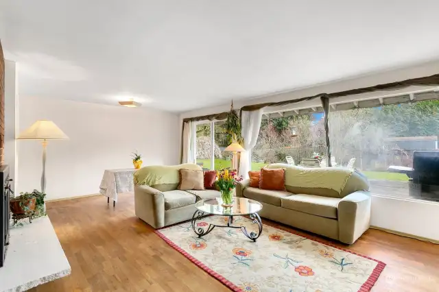 Living room with large picture windows and dining space with slider to back yard