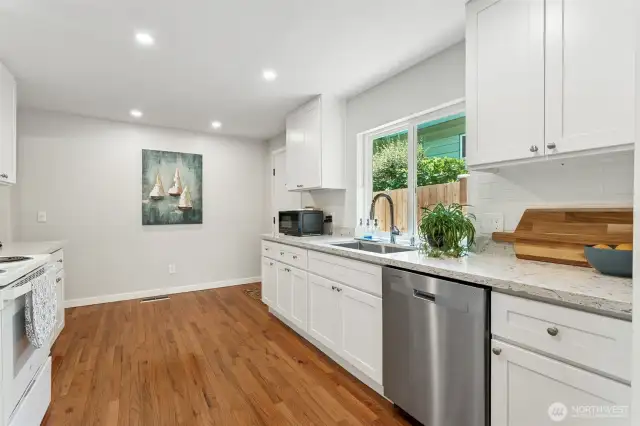 This view of your bright kitchen with another door leading out to the beautiful fenced back yard.