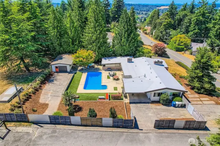 This private retreat blends timeless architecture with resort-style amenities. Tucked behind lush evergreens on a corner lot, this beautifully maintained home features an entertainer’s dream yard with a sparkling in-ground pool, spacious patio, covered outdoor lounge, and detached garage with bonus space. The open-concept interior flows seamlessly to the backyard through large sliders, creating the ultimate indoor/outdoor living experience. Enjoy a fully fenced yard, ample parking, and mature landscaping—all just minutes from shopping, schools, and freeway access. A rare gem with unforgettable curb appeal and functionality.