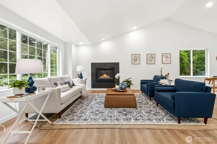 Step inside to a bright, open layout filled with natural light. Fresh paint, new trim, and updated flooring create a clean, modern feel from the moment you enter. The living room features vaulted ceilings and skylights that flood the space with daylight. A gas fireplace anchors the room, creating a warm and welcoming gathering space.