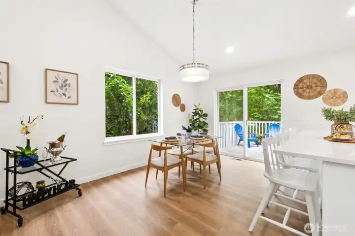 The dining area sits just off the spacious Trex deck, creating a seamless indoor-to-outdoor flow perfect for everyday living. Large windows frame the greenery outside, making meals feel connected to the natural surroundings while offering effortless access for entertaining.