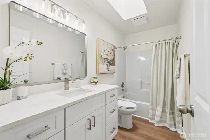 The updated hall bath includes modern fixtures and a clean, timeless design. Guests and household members alike will appreciate the light filled space with skylight and thoughtful upgrades.