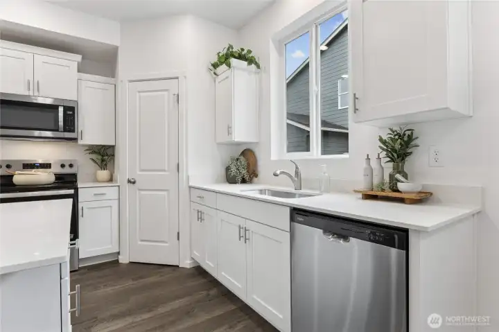 A close-up of the kitchen's sink area showcases the undermount sink, stylish arc faucet, and quartz countertops. Photos are representative only and may display different colors and or upgrades.