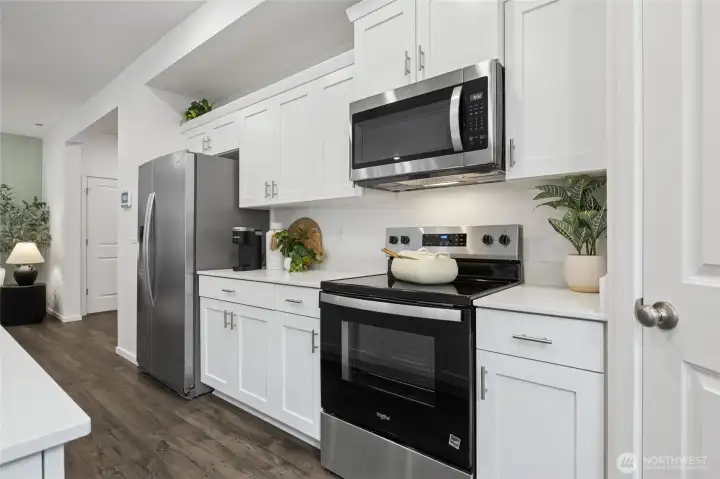 This close-up of the kitchen's cooking station showcases the stainless steel electric range, over-the-range microwave and plenty of cabinets. Photos are representative only and may display different colors and or upgrades.