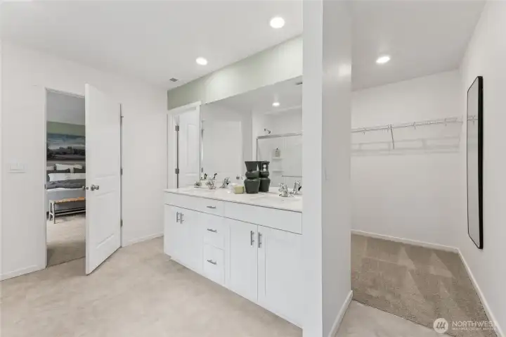 This angle of the owner's en-suite reveals the seamless connection between the double-sink vanity area and the expansive walk-in closet beyond, offering both luxury and practicality. Photos are representative only and may display different colors and or upgrades.