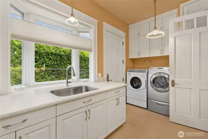 The large laundry room with a window overlooking the back yard, sink and door to back yard space.