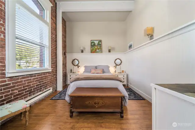 THE PRIMARY BEDROOM IS STYLISH AND ACCENTED BY A BRICK WALL