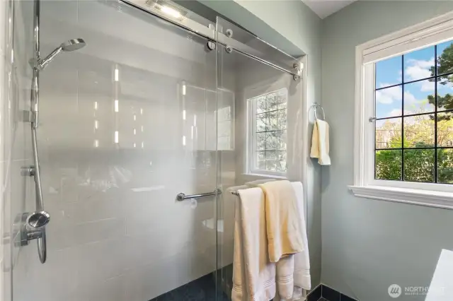 Tile shower with Grohe fixture (new in 2022), grab bars. Glass doors by Seattle Shower Door with ShowerGuard finish.