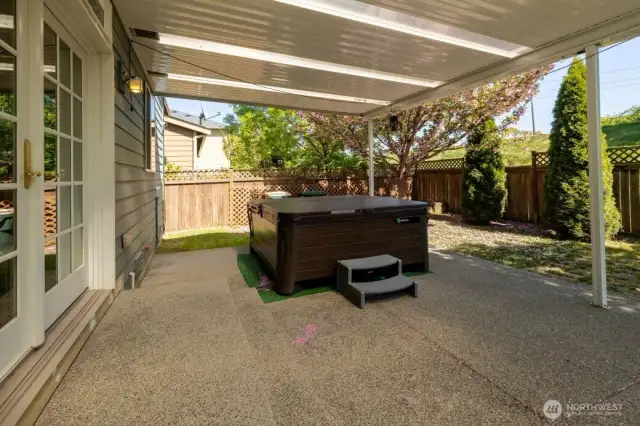 A place to relax! Covered back patio accessed by french doors with hot tub. Open space behind the fencing and the mountain view beyond.