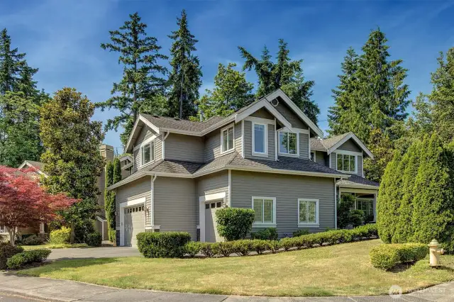 This beautifully maintained two-story home offers timeless curb appeal with classic gray siding, crisp white trim, and a welcoming covered entry. Nestled in a lush, tree-lined neighborhood, the home features a spacious three-car garage, manicured landscaping, and a quiet setting perfect for peaceful living.