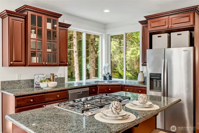 Sunlight pours through the oversized corner windows above the sink, offering serene views of the wooded backyard.