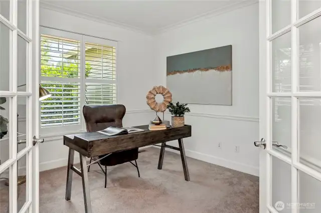 This private home office offers a quiet, light-filled retreat with French doors, classic millwork, and plantation-shuttered windows.