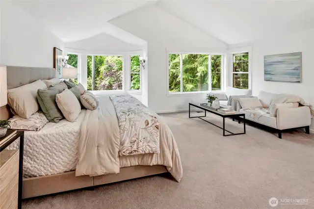 The luxurious primary suite is a true retreat, offering generous proportions, vaulted ceilings, and serene views of lush greenery through oversized windows
