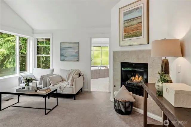 A sitting area with a cozy gas fireplace creates the perfect spot to unwind, while the soft neutral palette and plush carpeting add to the calming ambiance.