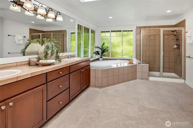 The spa-inspired primary bathroom offers a luxurious escape with its oversized soaking tub framed by large privacy windows that bathe the space in natural light.