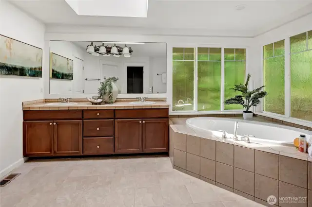 Dual vanities with warm wood cabinetry and expansive mirrors provide ample storage and prep space.