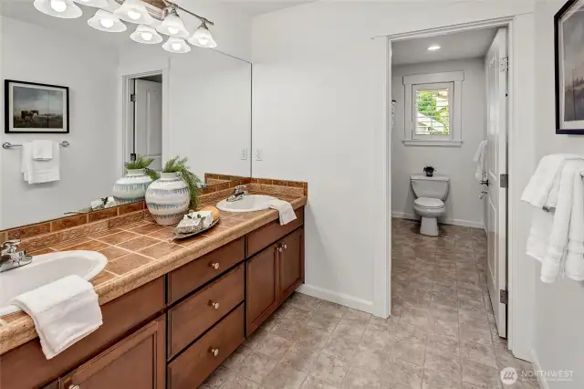 The main upstairs bath features dual sinks set in a spacious tile-topped vanity with plenty of storage below.