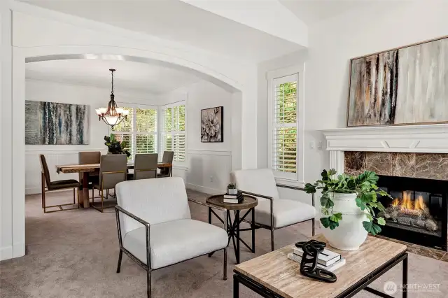 The formal living room flows seamlessly into the elegant dining area through a wide arched opening, creating a harmonious space for entertaining.