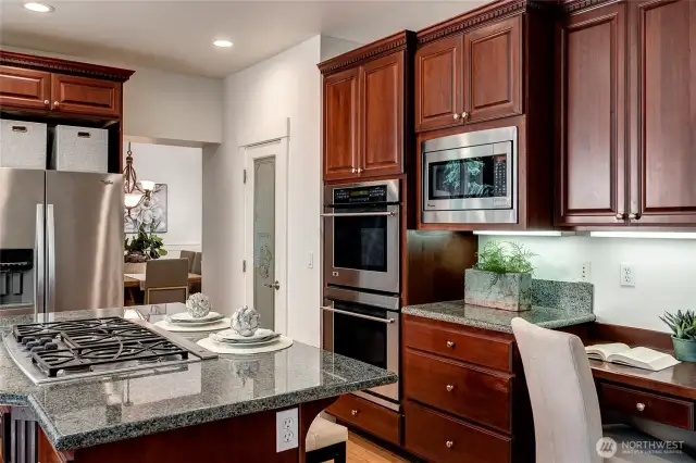 Stainless steel appliances, double ovens, and a built-in desk area add function and style, while a walk-in pantry provides ample storage.