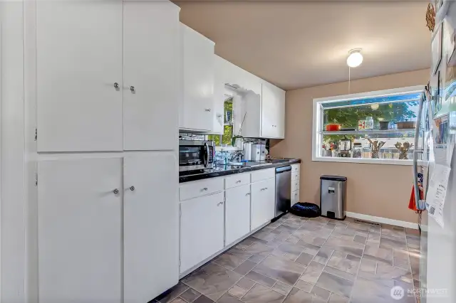 The kitchen is light and bright, featuring classic white cabinets, granite tile countertops, and a stylish tiled backsplash. With easy access to all your pots, pans, and dishes, meal prep is a breeze. All appliances stay, making this kitchen as functional as it is welcoming.