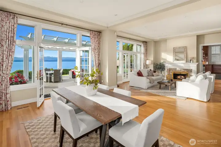 Olympic Mountains in the distance with Kitchen eating area, Living Room, and Den beyond. The entire west-facing side features commanding windows and French doors.