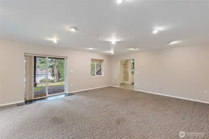 Lower level living room: Private sliding glass door entrance to back yard and beautiful west-facing lake views! Entry to hall and kitchen beyond.