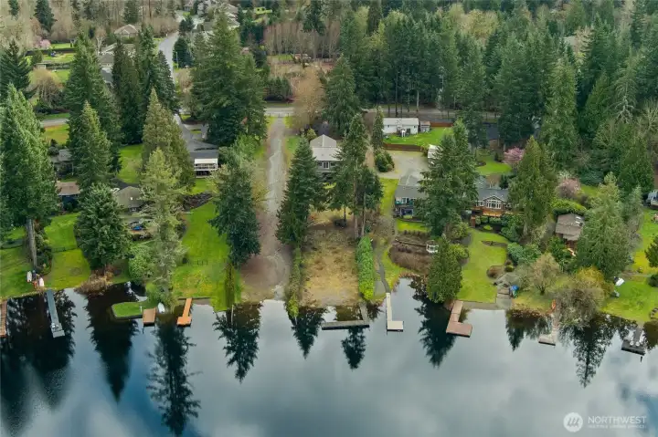 Long backyard to low bank waterfront with private dock + view of neighbors along the lake.