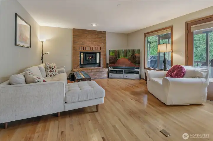 Living room with wood fireplace insert looks out over the back yard and greenbelt.