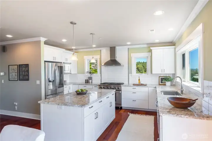 Designed for both beauty and function, the Chef's kitchen showcases a generously sized granite island, ample storage, walk-in pantry and a suite of upgraded stainless steel appliances including a six burner gas range and convection oven. Stone countertops provide the perfect workspace to take in the lake views.