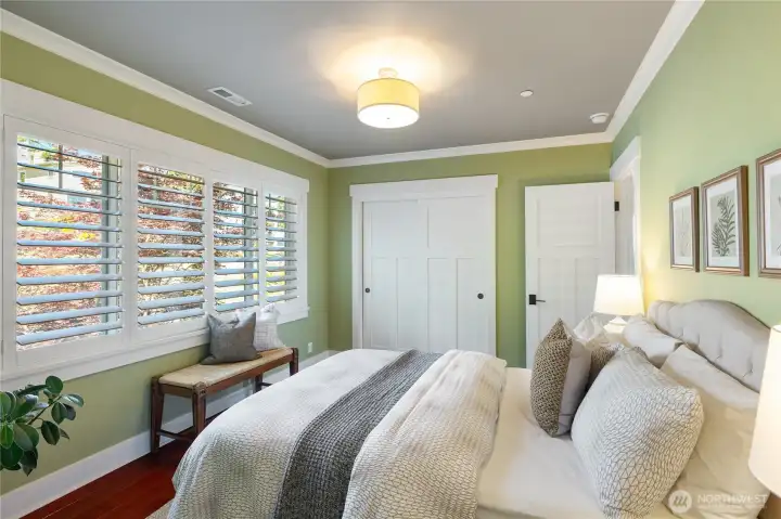 Main level bedroom with large storage closets and custom wood plantation shutters.