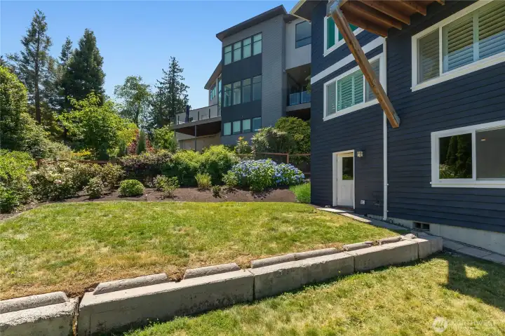 Fenced back yard with gardens and level grassy area.