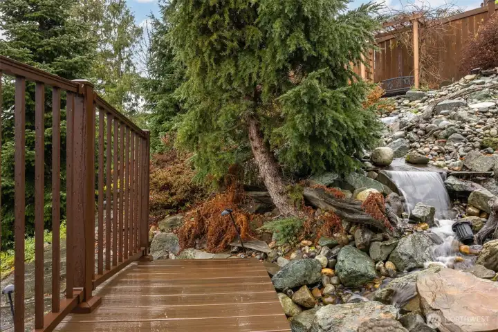 Looking across the bridge to the  stone walkway beyond the waterfall.