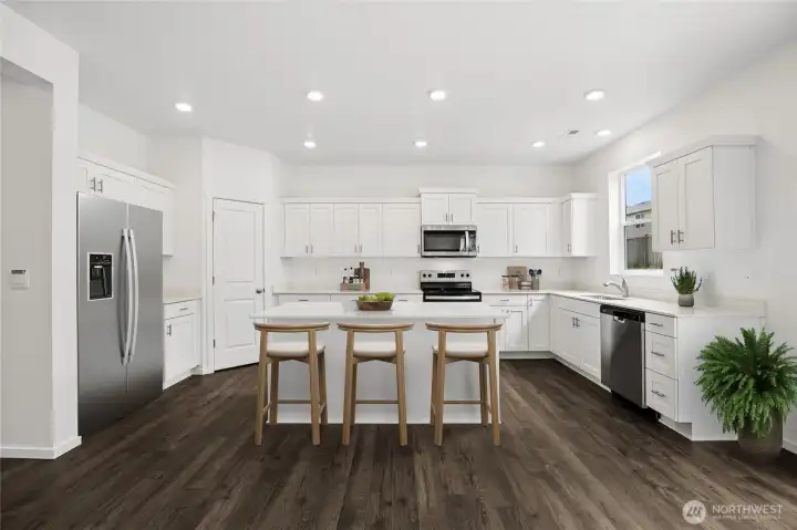 Kitchen boasts lots of cabinets and room at the island for gathering.  Virtually staged.