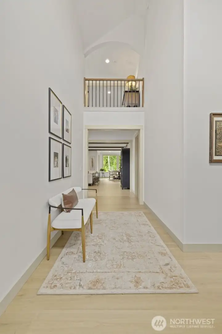 The light-filled entry features elegant arched architecture, hardwood floors, and a dramatic open balcony overlook.