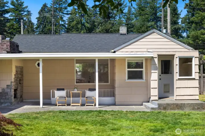 The rear of the home features a built-in chimney fireplace, access stairs to the basement, a covered patio area, and covered rear entrance to the home.