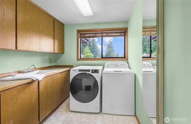 Well-Appointed Main Floor Utility Room: Generously sized and thoughtfully designed, featuring ample upper and lower cabinetry for organized storage and effortless functionality.