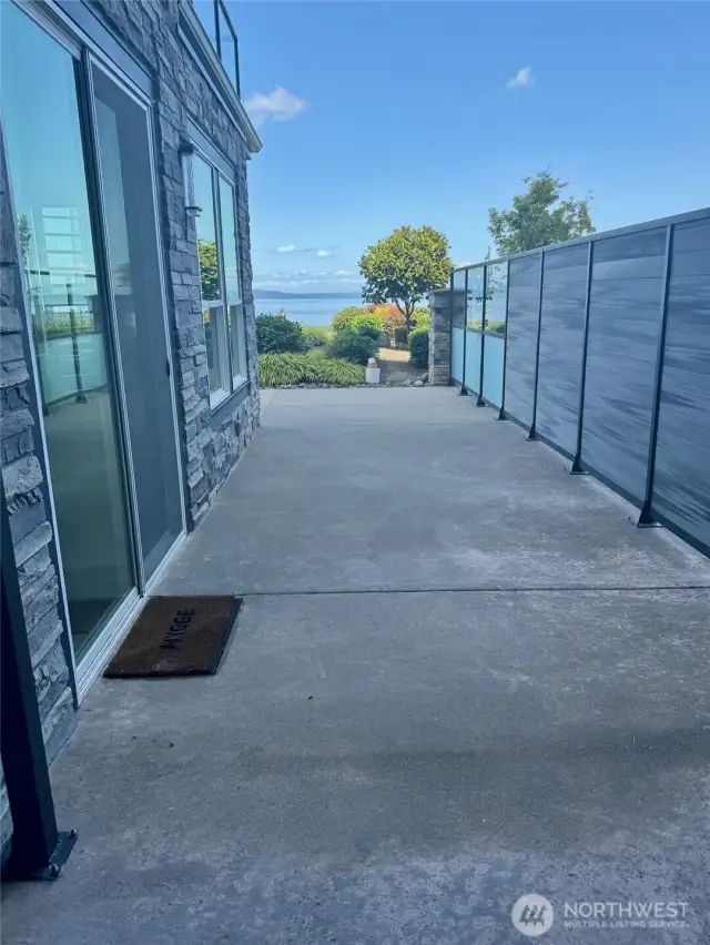 Another view of the side patio taken from the primary bedrooom.  You can see the water view from here! Door mat is in front of the slider that leads from the kitchen/living room area.
