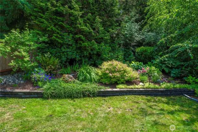 Lush Garden Featuring Vibrant Flowers, Neat Shrubs, and Towering Trees.