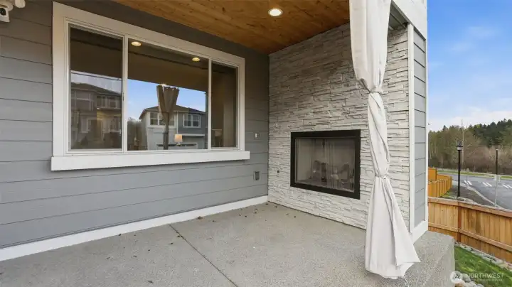 Enjoy fresh air and comfort on this covered patio with a stylish stone fireplace.