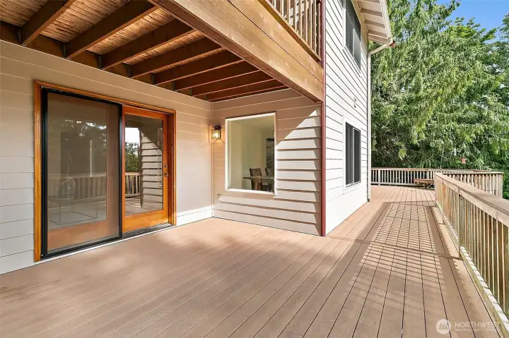 View of the deck outside the living room with a view to the large deck off the kitchen/dining room.  Deck above is the private outdoor space for the primary suite.