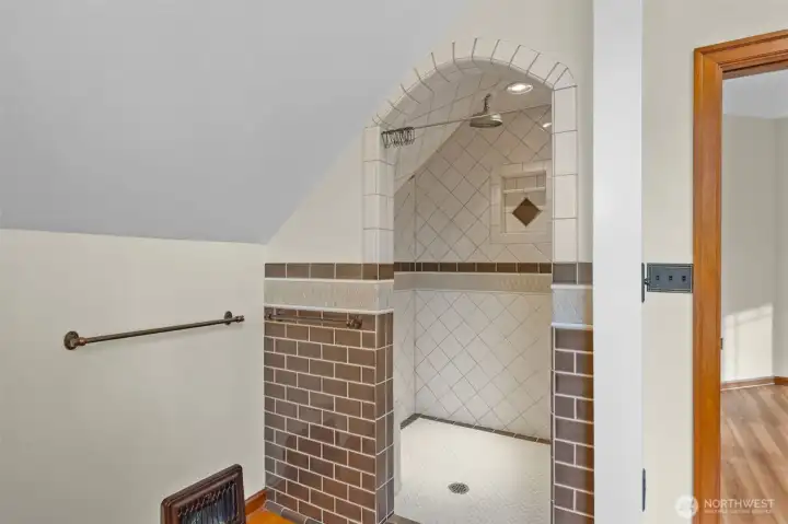 Primary shower has 3 shower heads including 1 rain shower head and a tiled bench.