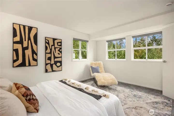 Main floor primary bedroom is surrounded by nature.