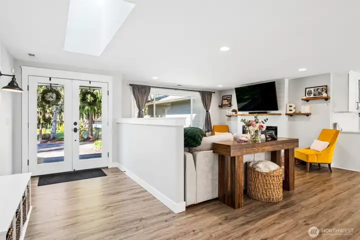 The half wall creates a gentle separation from the entry without closing anything off, so the living room still feels connected while giving you a natural place to anchor furniture and keep a little privacy from the front door. A large picture window brings in great light and a view of the front yard, while recessed lighting keeps the space bright and flexible into the evening. The fireplace wall sets up as the clear focal point, with a TV mount already in place above the mantle, making it easy to settle in and enjoy the space from day one.